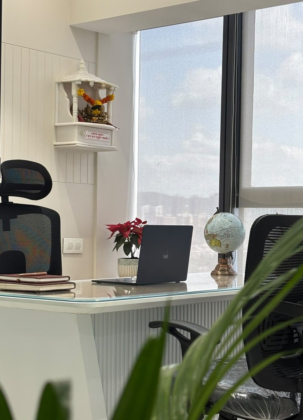 A calm, bright workspace with a white desk, a window view and indoor plants